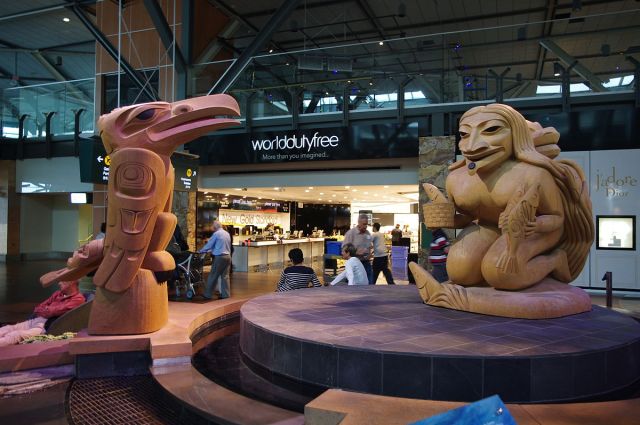 The Story of Fog Woman and Raven, sculpture by Dempsey Bob on exhibit at the Vancouver International Airport, 2012 photo by Eviatar Bach on Wikipedia at https://commons.wikimedia.org/wiki/File:The_Story_of_Fog_Woman_and_Raven_4.JPG#mw-jump-to-license